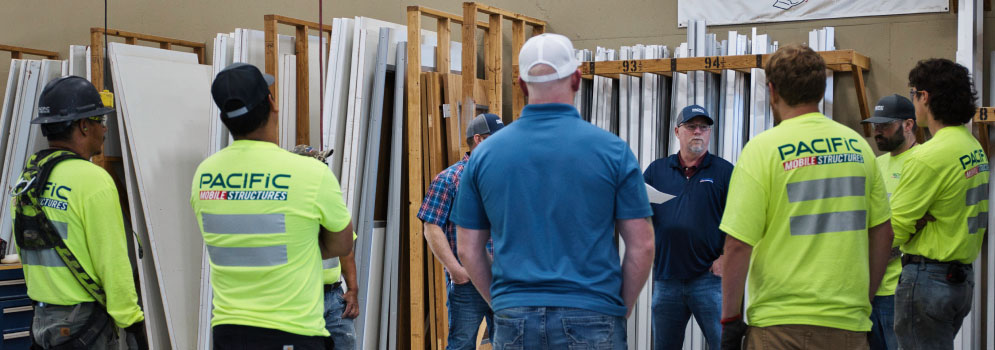 Pacific Mobile Structures construction team collaboratively inspects modular building components, showcasing their commitment to quality