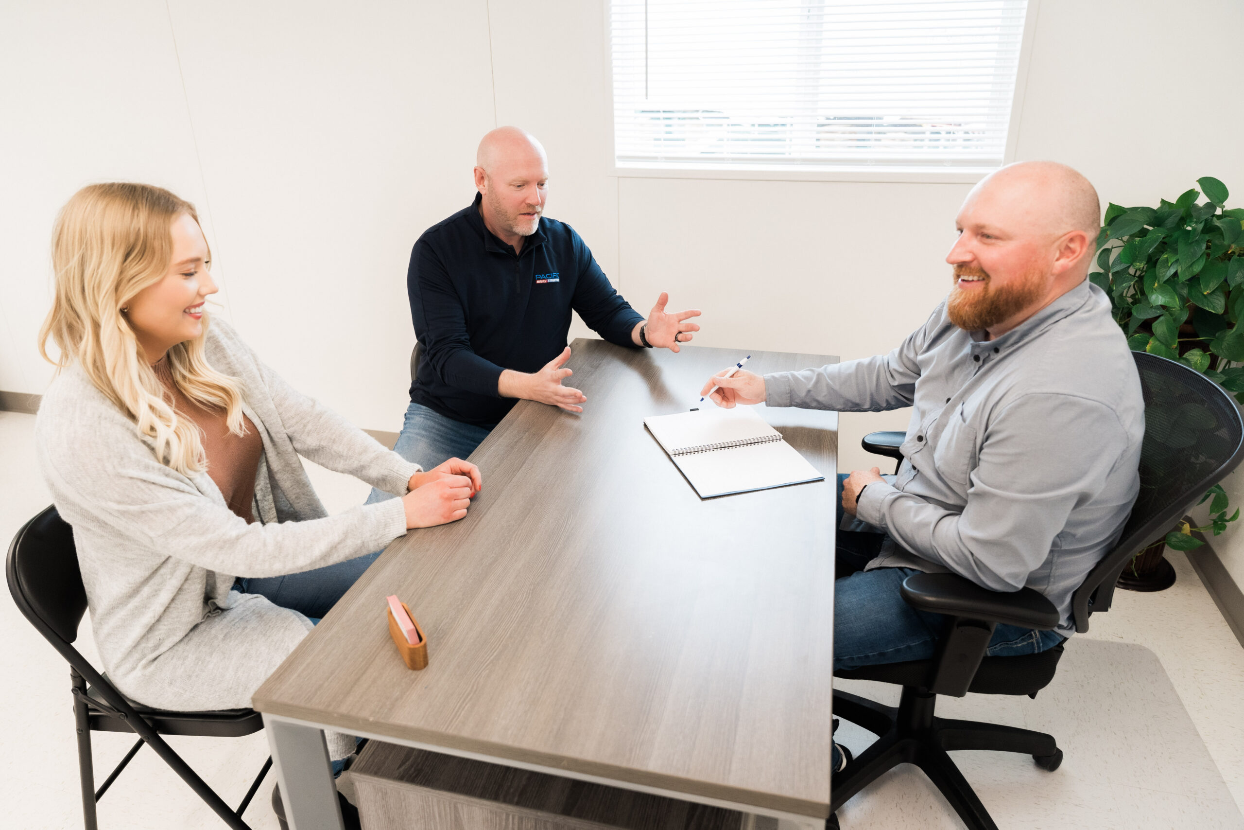 Three Pacific Mobile Structures team members collaborate in a well-lit modular office space, discussing project